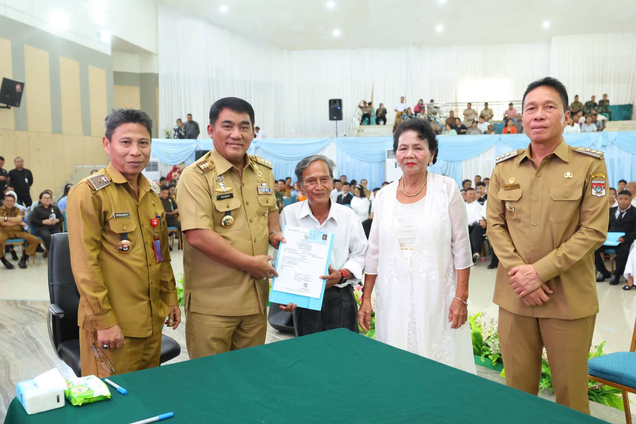 Gubernur YSK menyerahkan dokumen kependudukan secara simbolis pada acara Pencatatan Perkawinan Massal Pemprov Sulut di Aula Mapalus, Manado, Selasa (21/7/2026)