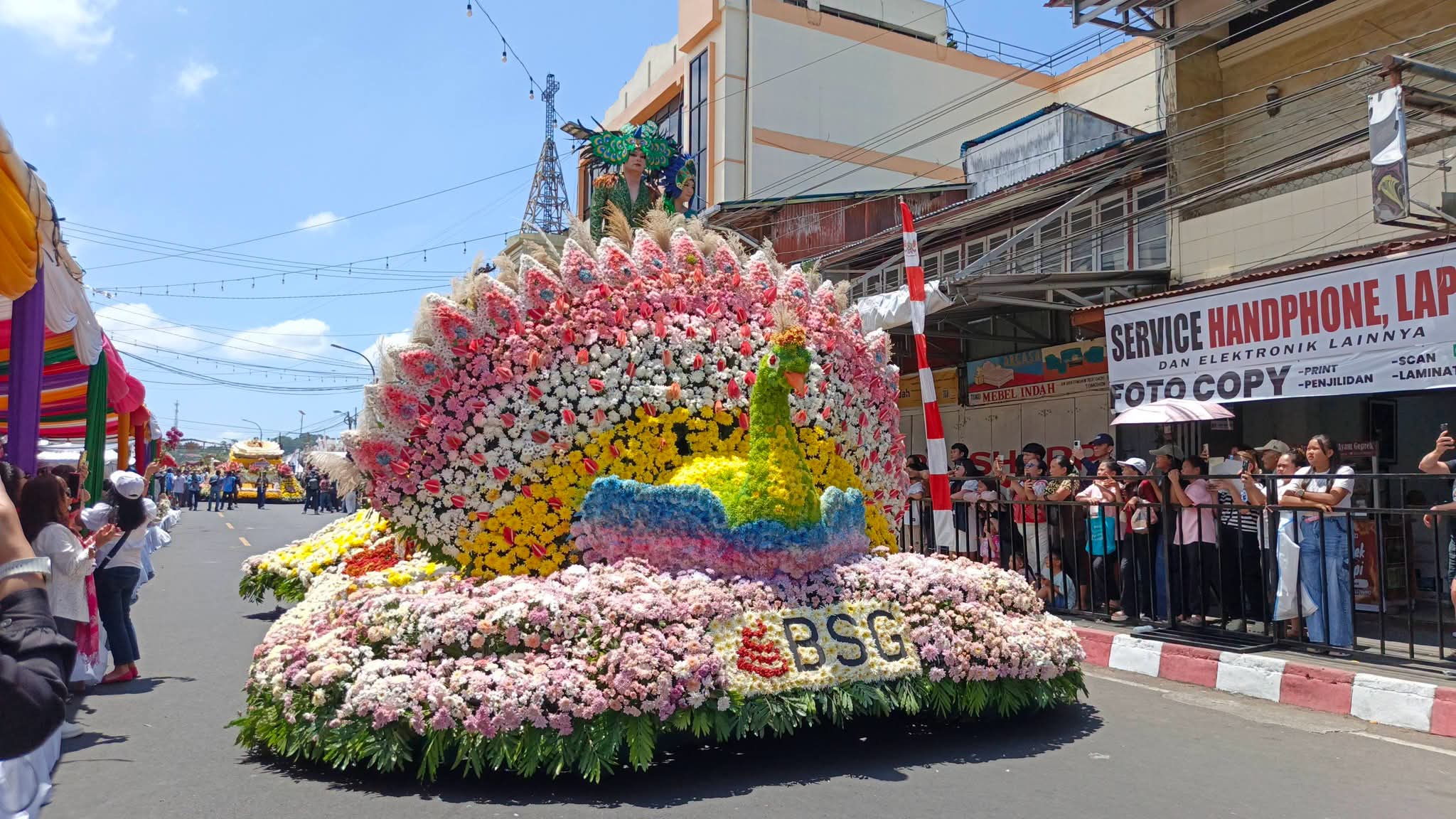 Float Bank SulutGo (BSG) berbentuk burung merak raksasa dengan perpaduan warna merah muda, putih, ungu, kuning dan hijau muda melintas di depan tamu VIP dalam Tournament of Flowers (ToF) TIFF 2026 di pusat Kota Tomohon, Sabtu 8/8/2026.(dok.ist)